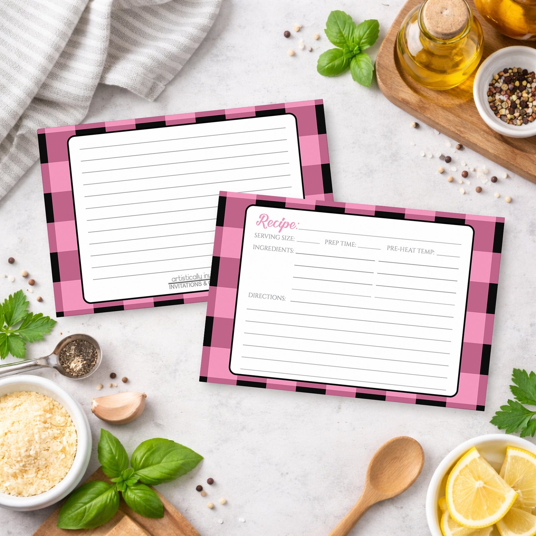 Two Light Pink and Black Buffalo Plaid Recipe Cards on a kitchen counter with ingredients.