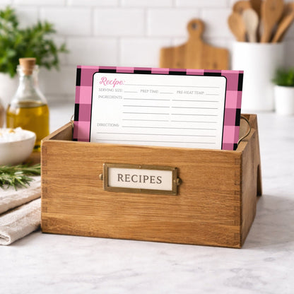 Wooden recipe box with a Light Pink and Black Buffalo Plaid Recipe Card on a kitchen counter.