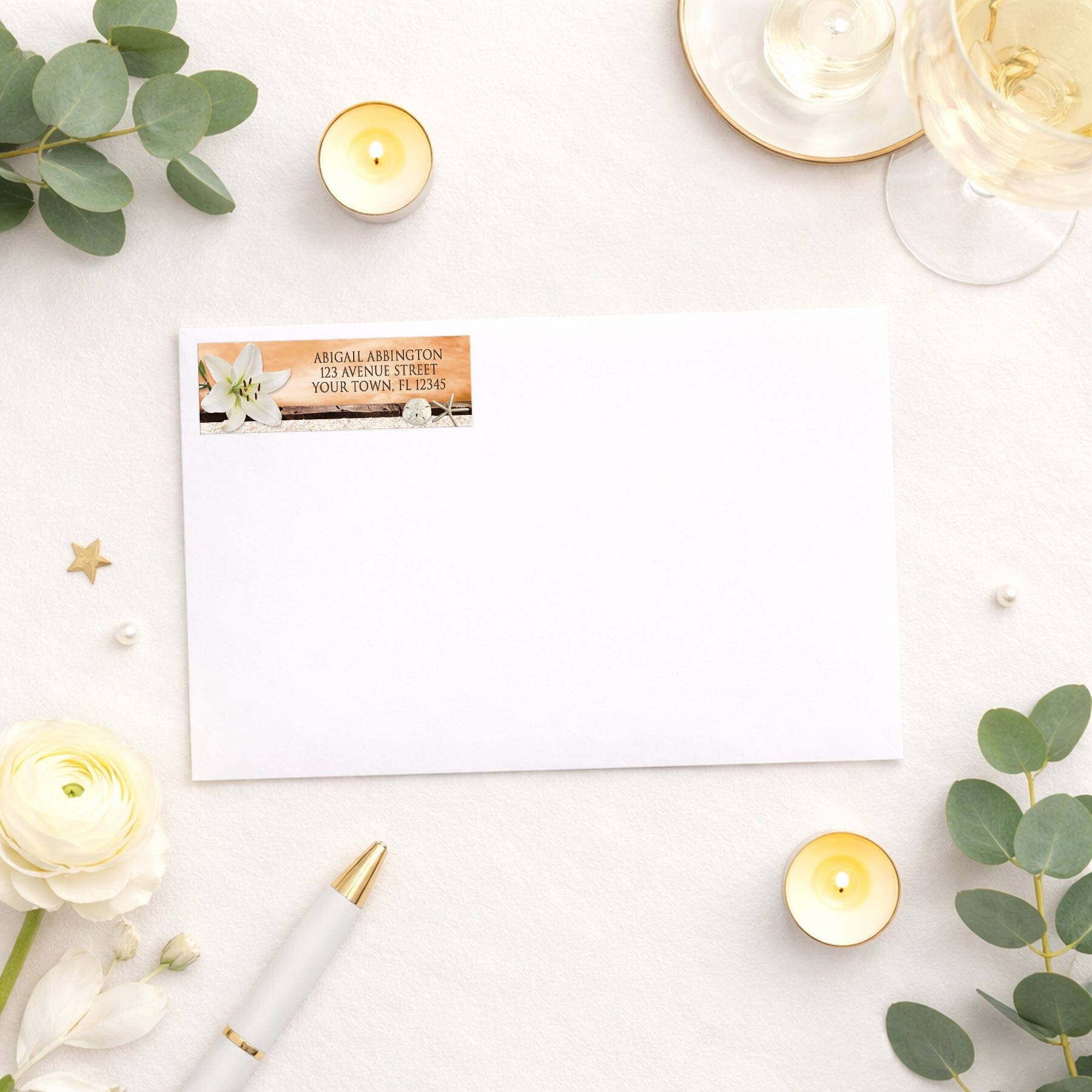 Lily Seashells and Sand Autumn Beach Address Label shown on a white envelope with wedding and shower supplies