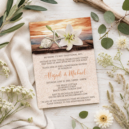 Lily Seashells and Sand Autumn Beach Honeymoon Shower Invitation shown on a light wooden surface with summer plants.