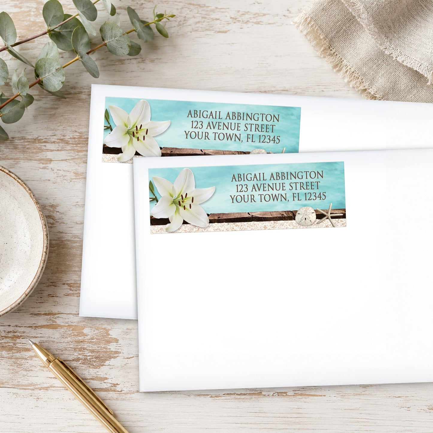 Lily Seashells and Sand Beach Address Labels shown on two white envelopes on a rustic wood surface with a pen.