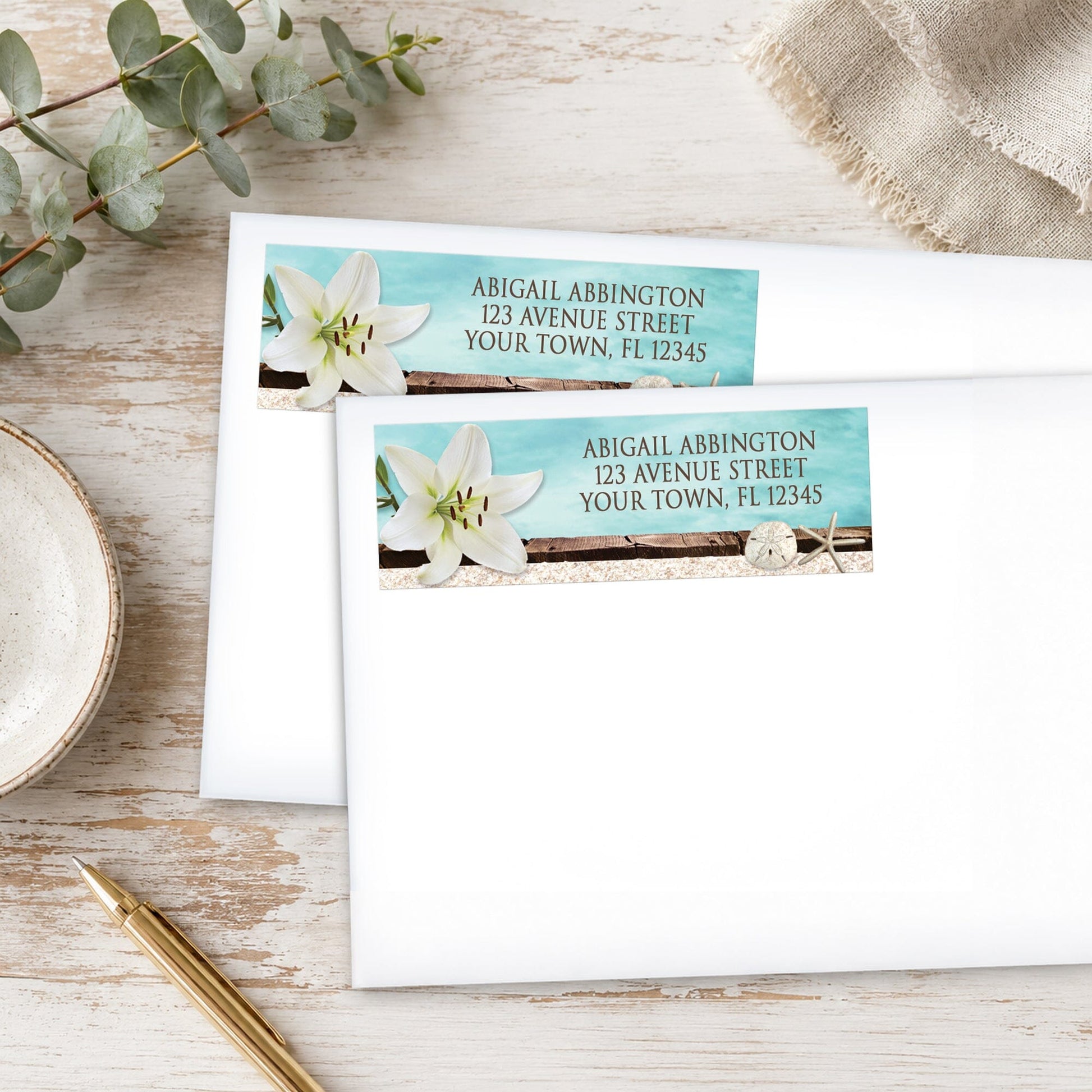 Lily Seashells and Sand Beach Address Labels shown on two white envelopes on a rustic wood surface with a pen.