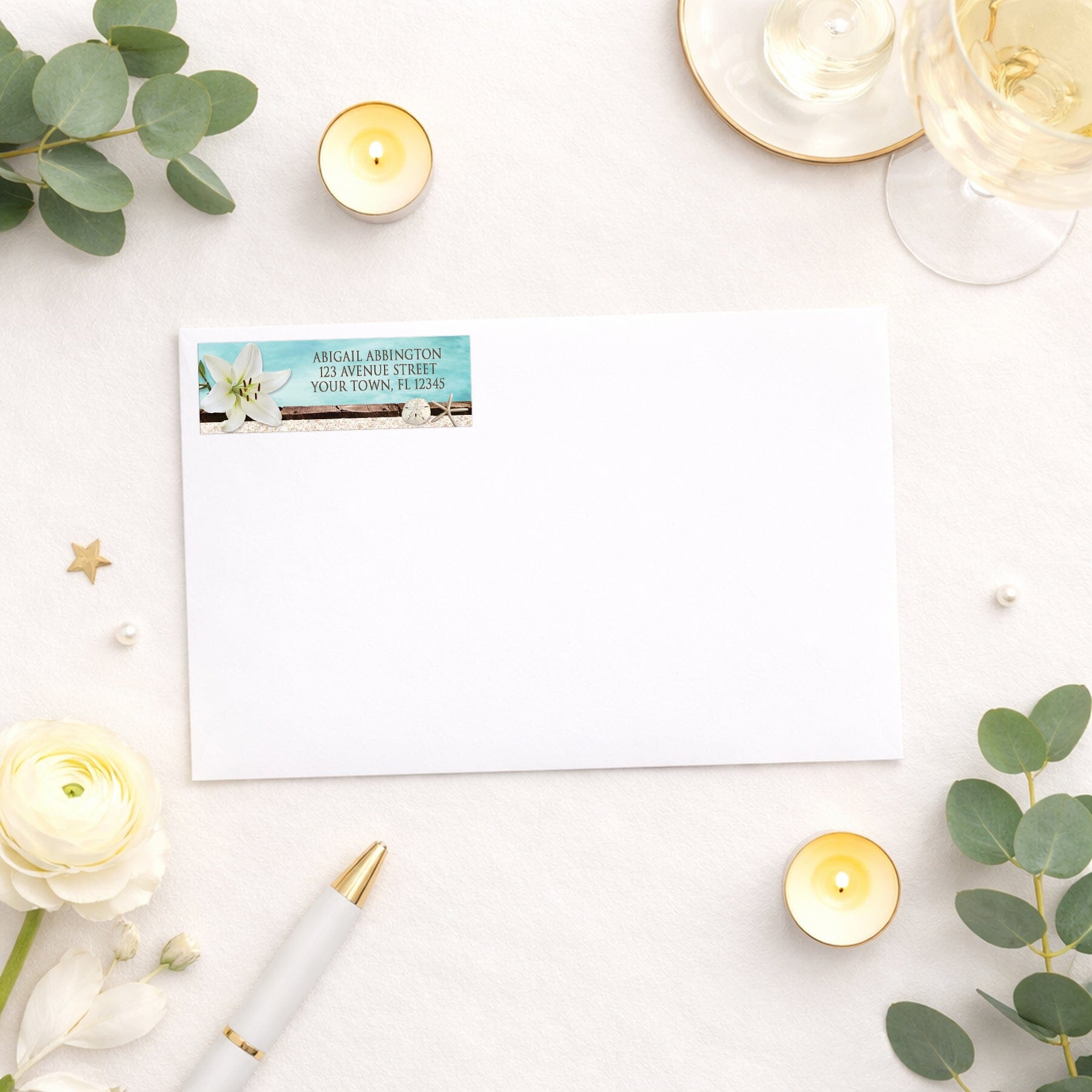 Lily Seashells and Sand Beach Address Label shown on a white envelope with elegant supplies