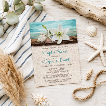 Lily Seashells and Sand Beach Couples Shower Invitation shown on a light wooden surface with seashells and coastal decor.