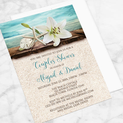 Lily Seashells and Sand Beach Couples Shower Invitation shown at an angle on a marble surface with a white envelope.