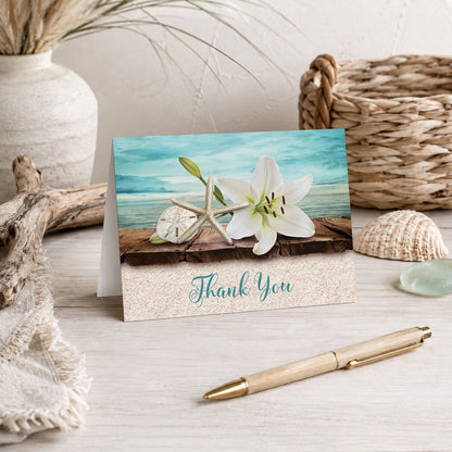 Lily Seashells and Sand Beach Thank You Card shown on a tabletop with a pen, vase, and beach house decor.