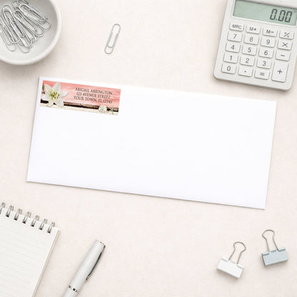 Lily Seashells and Sand Coral Beach Address Label shown on a white envelope with everyday office supplies