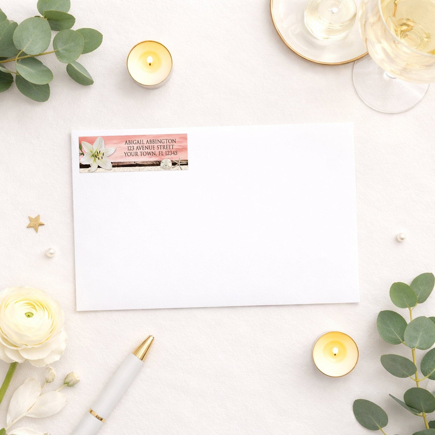 Lily Seashells and Sand Coral Beach Address Label shown on a white envelope with wedding and shower supplies