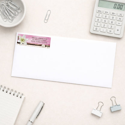 Lily Seashells and Sand Magenta Beach Address Label shown on a white envelope with everyday office supplies