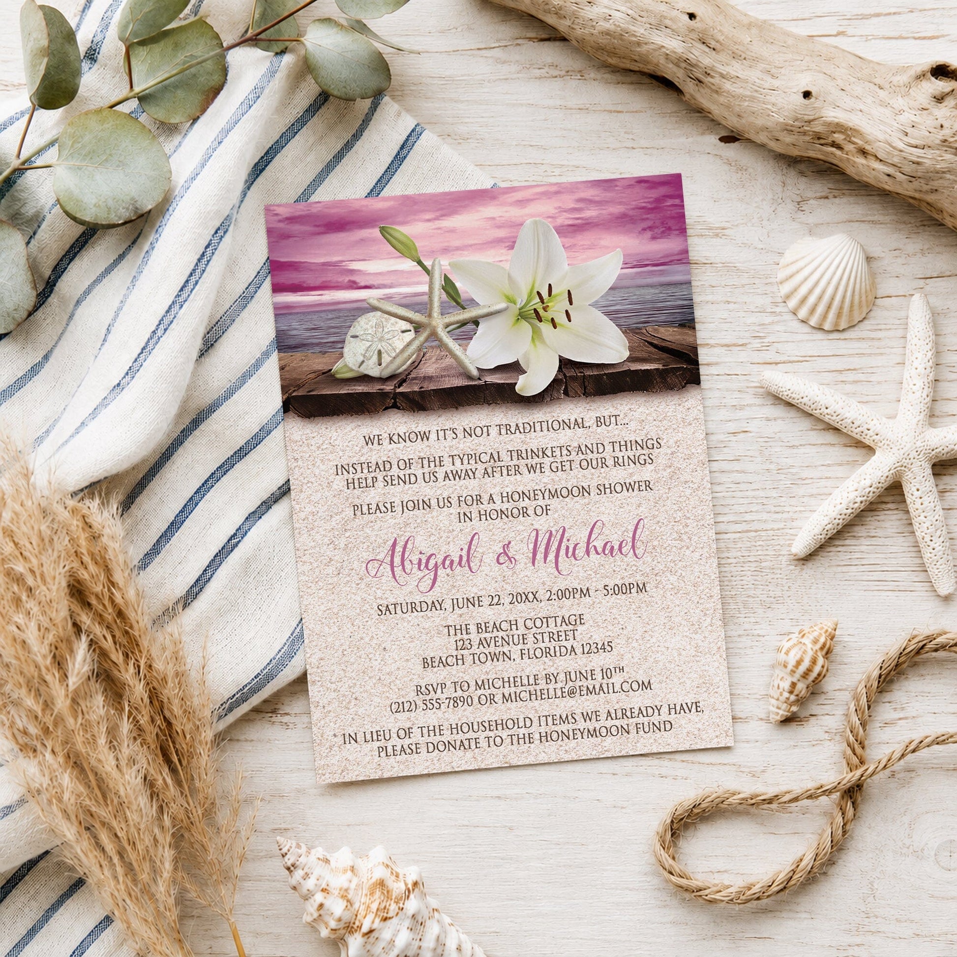 Lily Seashells and Sand Magenta Beach Honeymoon Shower Invitation shown on a wooden surface with seashells and beach decor.