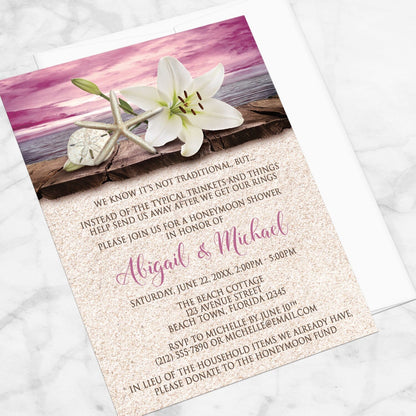 Lily Seashells and Sand Magenta Beach Honeymoon Shower Invitation shown at an angle on a marble surface with a white envelope.