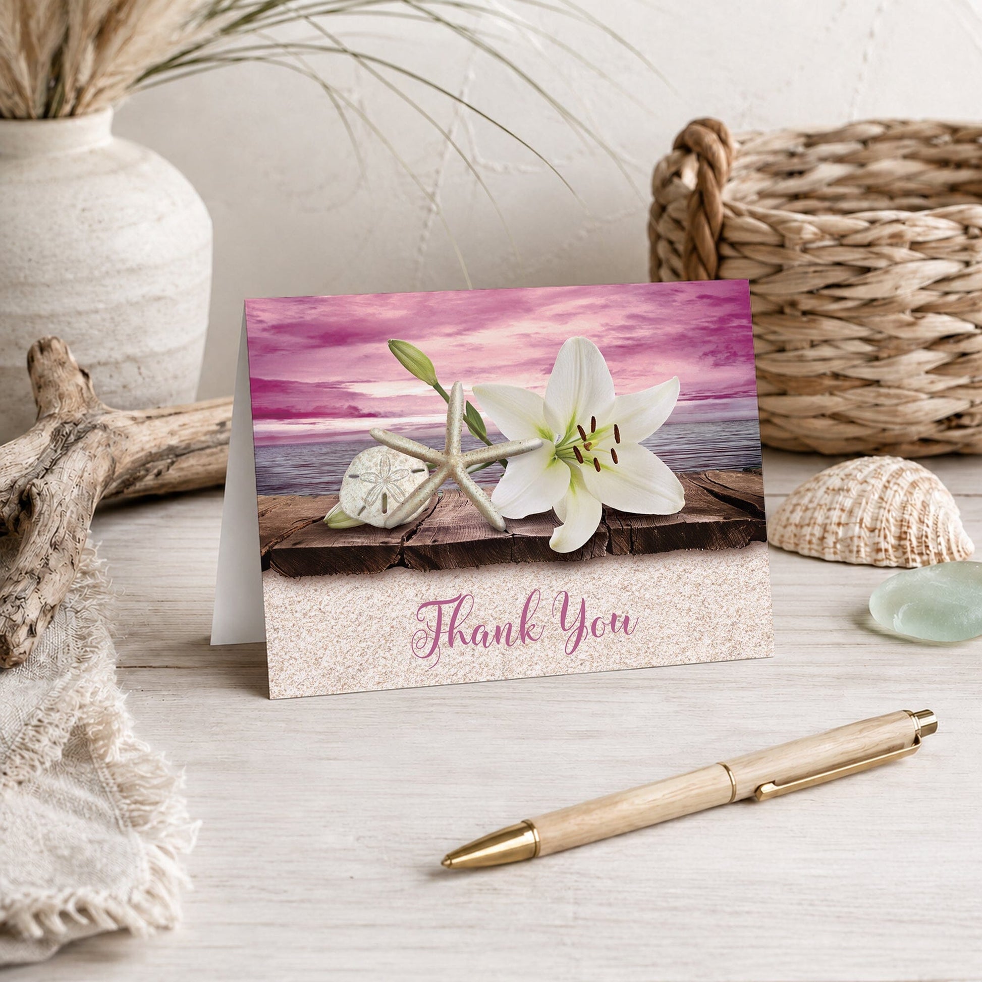 Lily Seashells and Sand Magenta Beach Thank You Card shown on a beach house tabletop with a vase, coastal decor, and a pen.