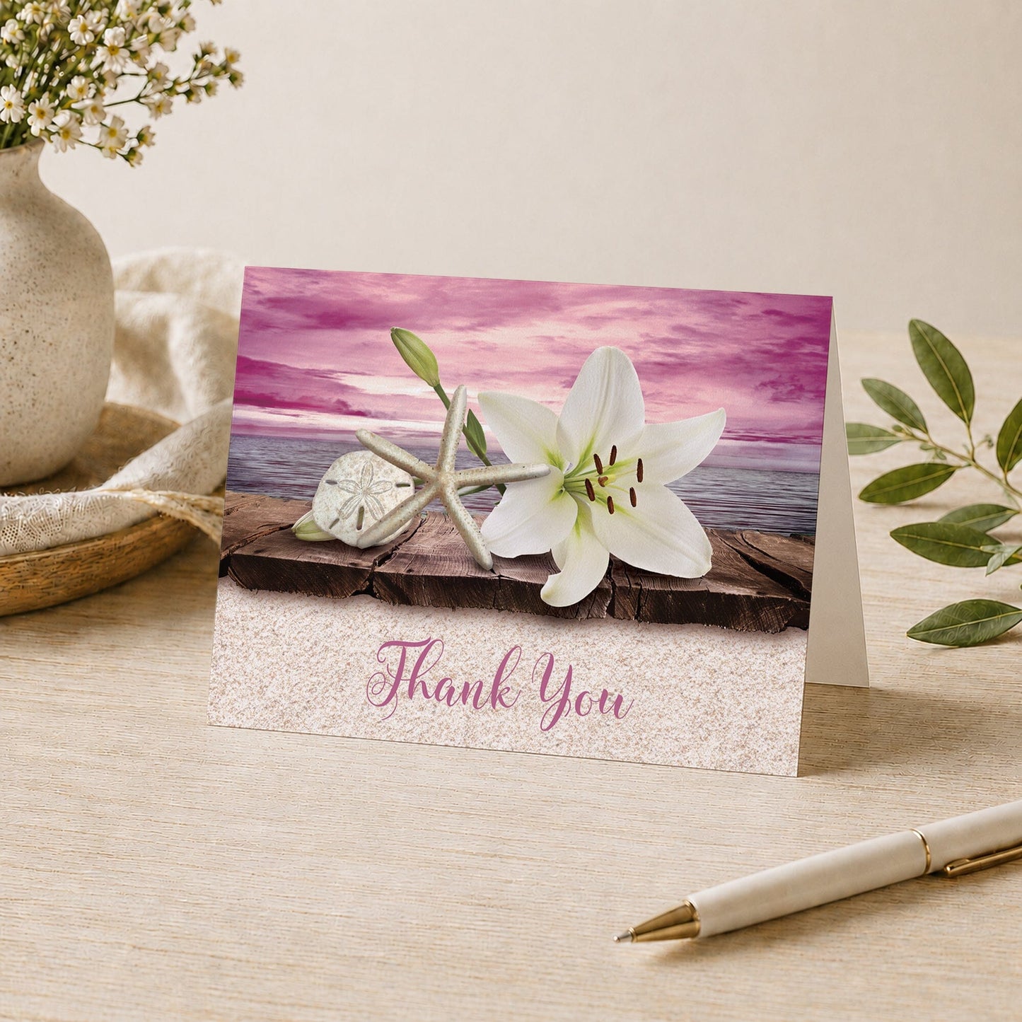Lily Seashells and Sand Magenta Beach Thank You Card shown on a desk with a vase, plants, and a pen.