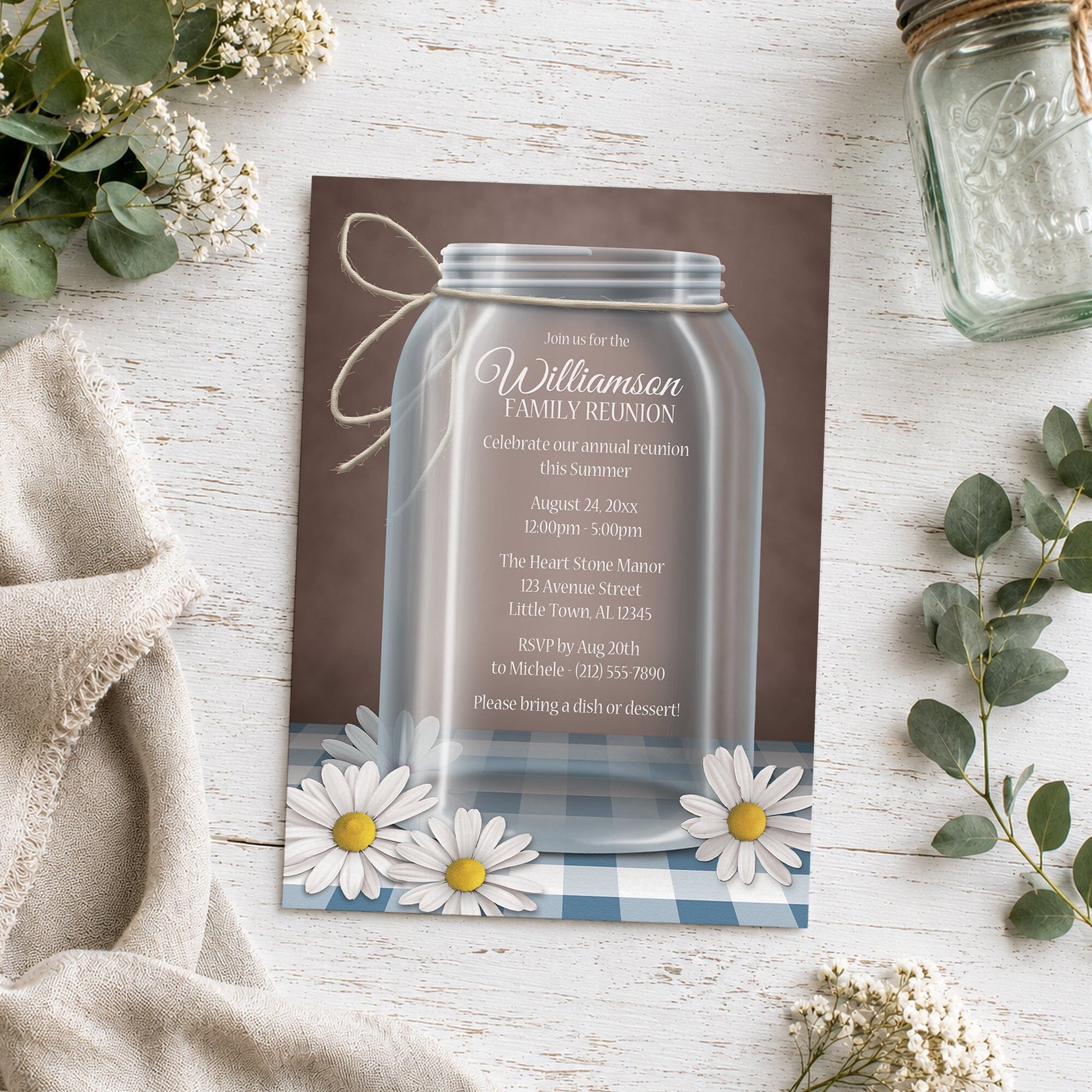 Mason Jar Daisy Blue Gingham Family Reunion Invitation shown on a light wooden surface with plants and a small mason jar.