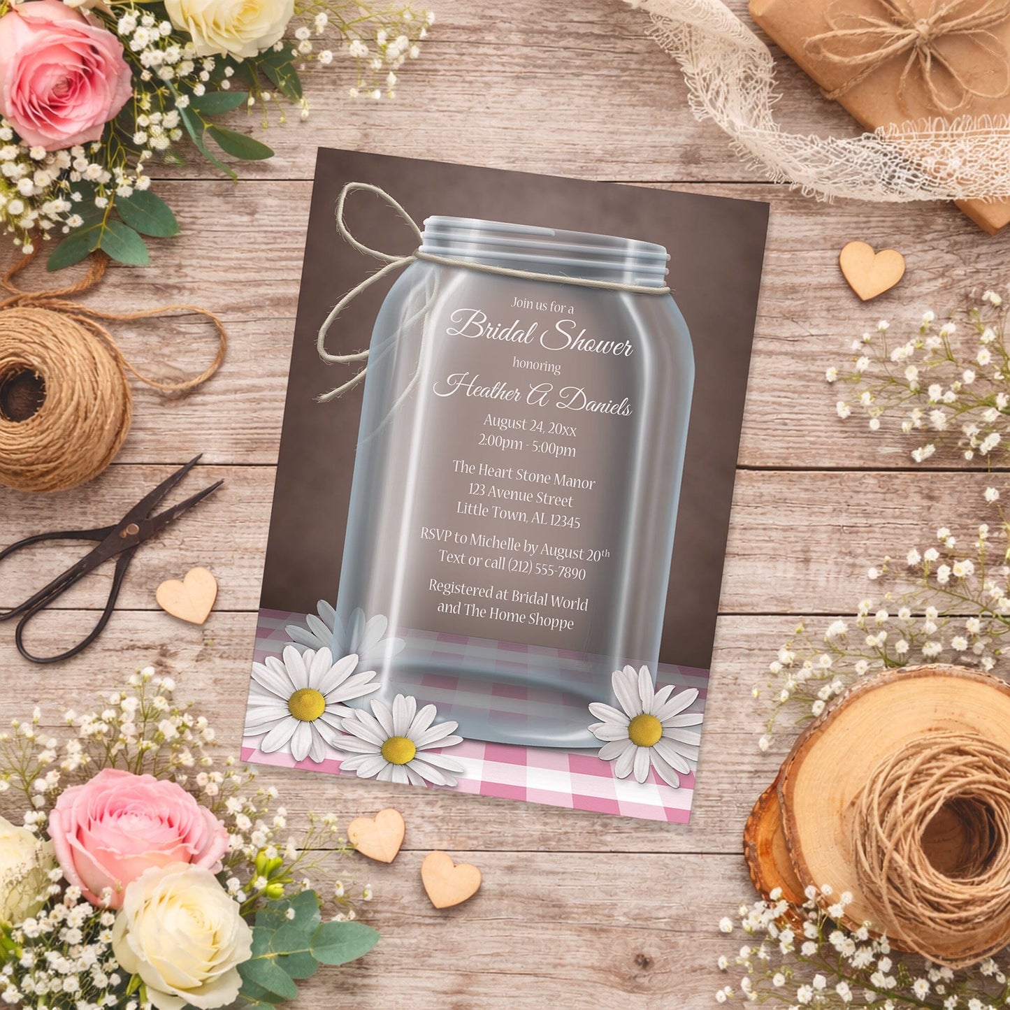 Mason Jar Daisy Pink Gingham Bridal Shower Invitation on a wooden surface with flowers and decorations.
