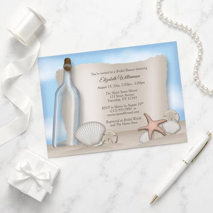 Seashell-themed Message from a Bottle Beach Bridal Shower Invitation on a marble surface with a gift box and pen.
