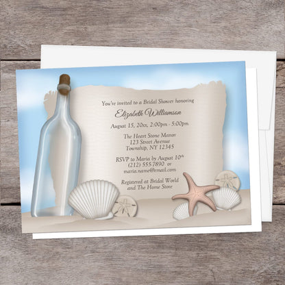 Seashell-themed bridal shower invitation with an illustrated bottle and sand, shown with a white envelope on a wooden background