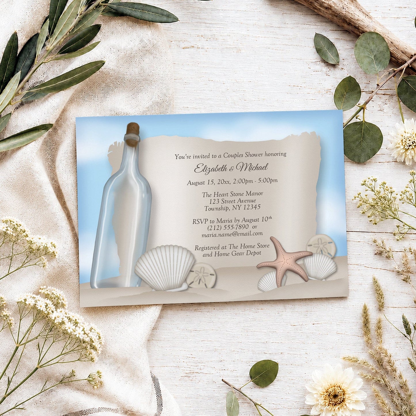 Message from a Bottle Beach Couples Shower Invitation shown on a light wooden surface with spring and summer plants.