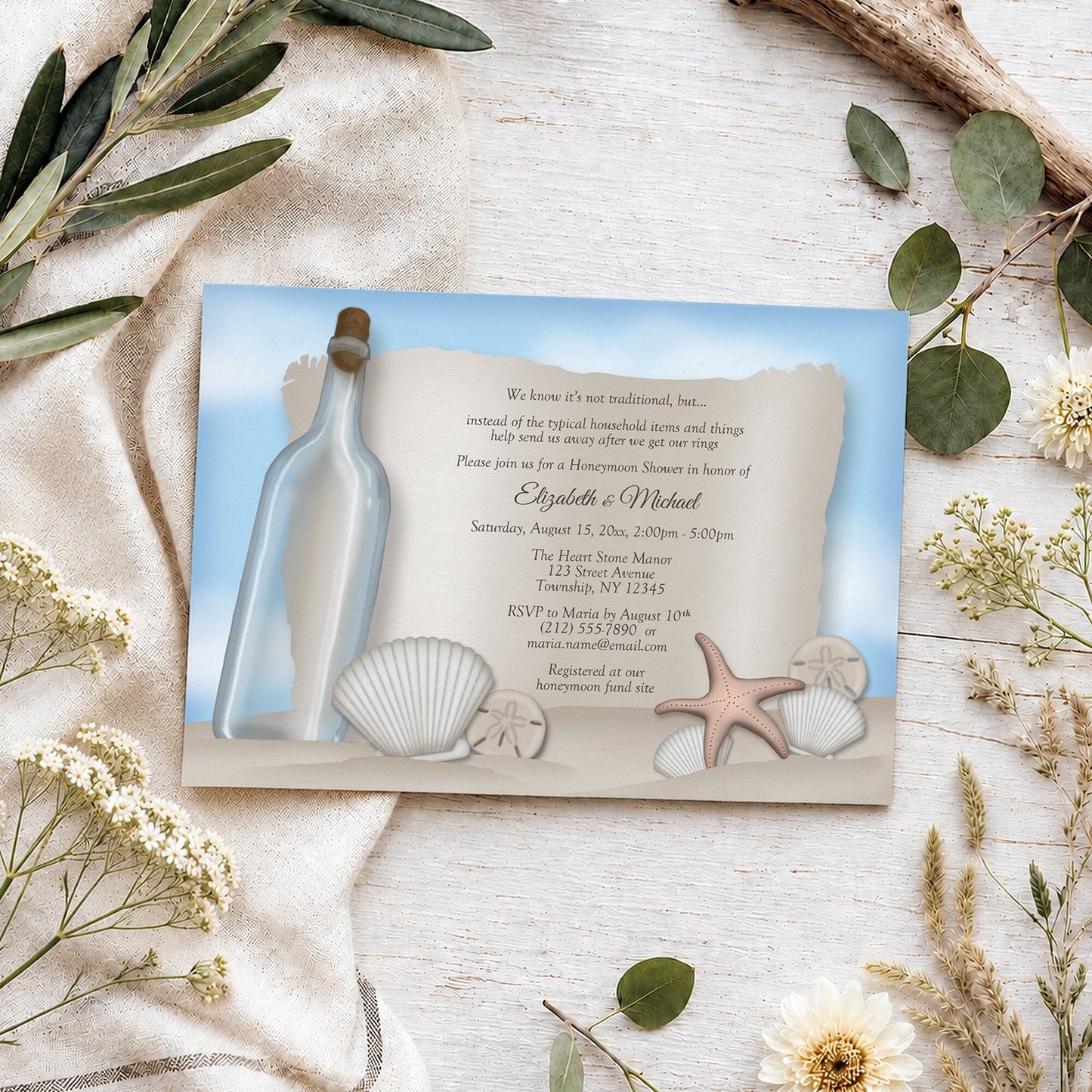 Message from a Bottle Beach Honeymoon Shower Invitation shown on a light wooden surface with summer plants.