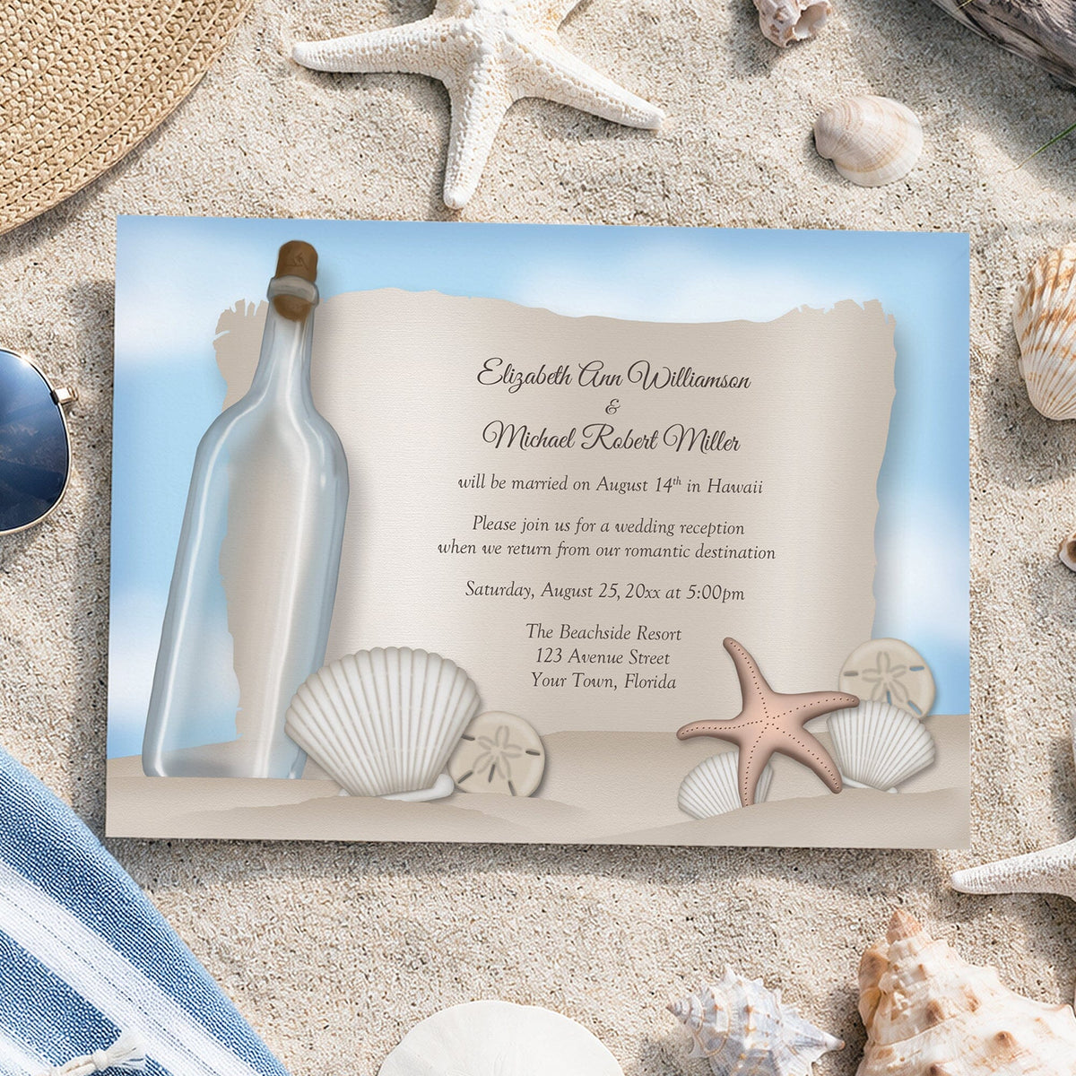 Beach reception only invitation with illustrated corked glass bottle beside a parchment-style message, seashells, sand dollars, pink starfish, and pale blue background, styled on a sandy beach background with starfish, shells, a straw hat, and a blue striped towel.