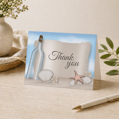 Message from a Bottle Beach Thank You Card shown on a tabletop with a vase, plants, and a pen.