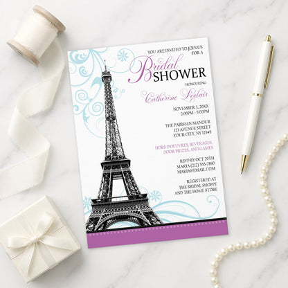 Modern Eiffel Tower Purple Parisian Bridal Shower Invitation shown on a marble surface with a white gift box, pen, ribbon, and pearls.
