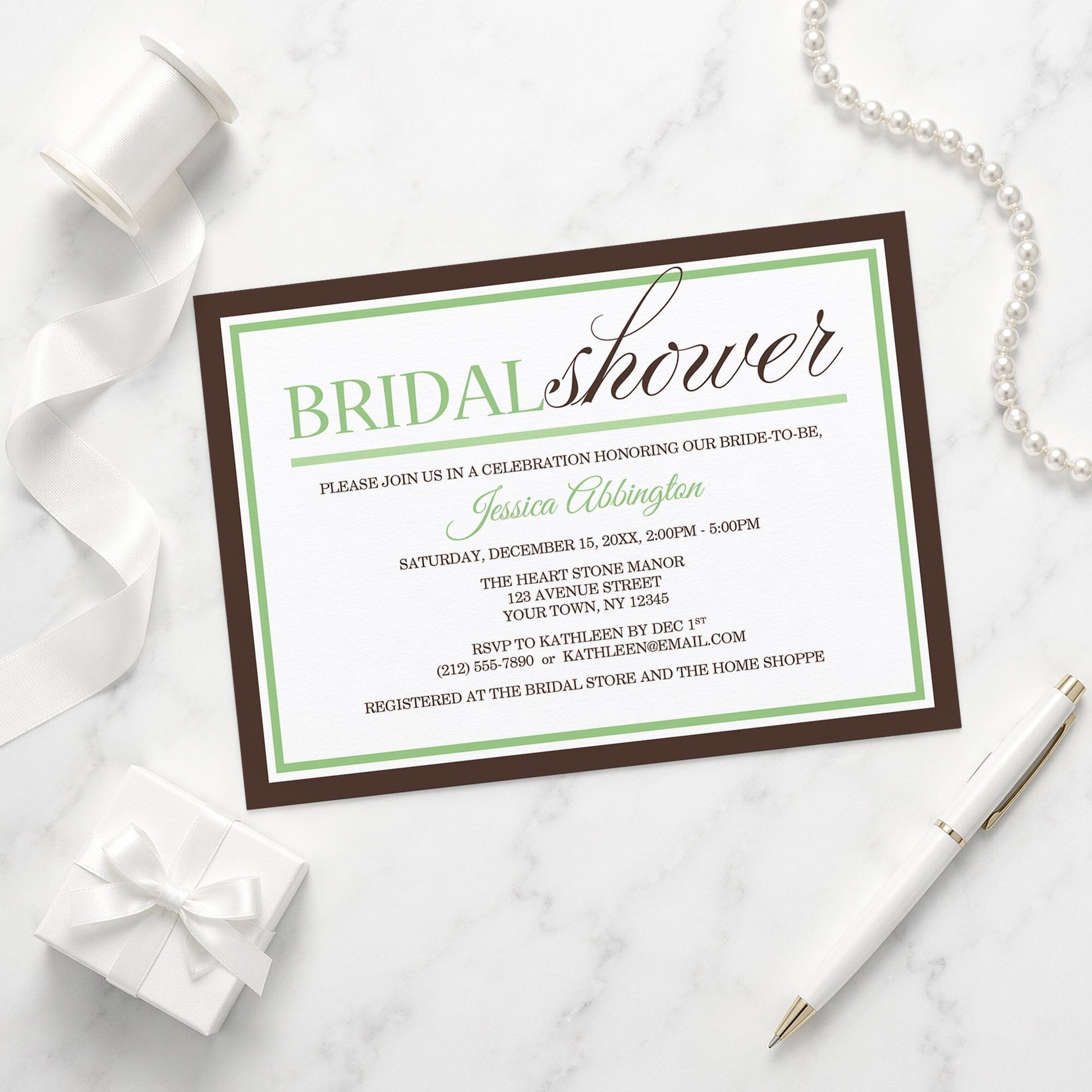 Modern Green and Brown Bridal Shower Invitation shown on a marble surface with a white gift box, pen, ribbon, and pearls.