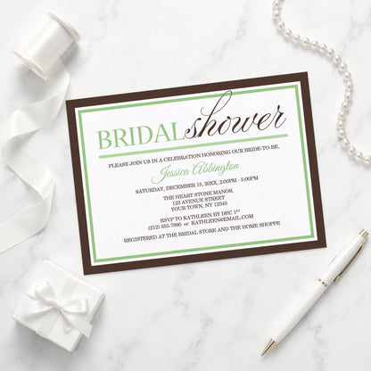 Modern Green and Brown Bridal Shower Invitation shown on a marble surface with a white gift box, pen, ribbon, and pearls.