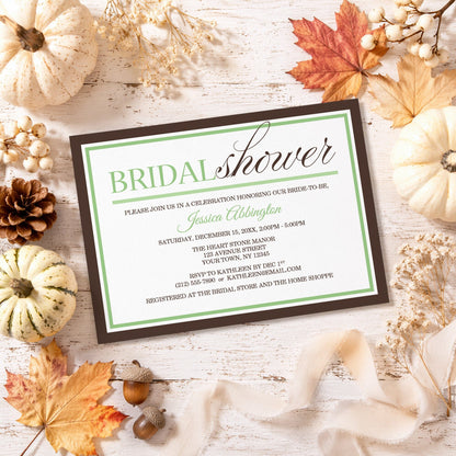 Modern Green and Brown Bridal Shower Invitation shown on a rustic surface with fall leaves and autumn decor.