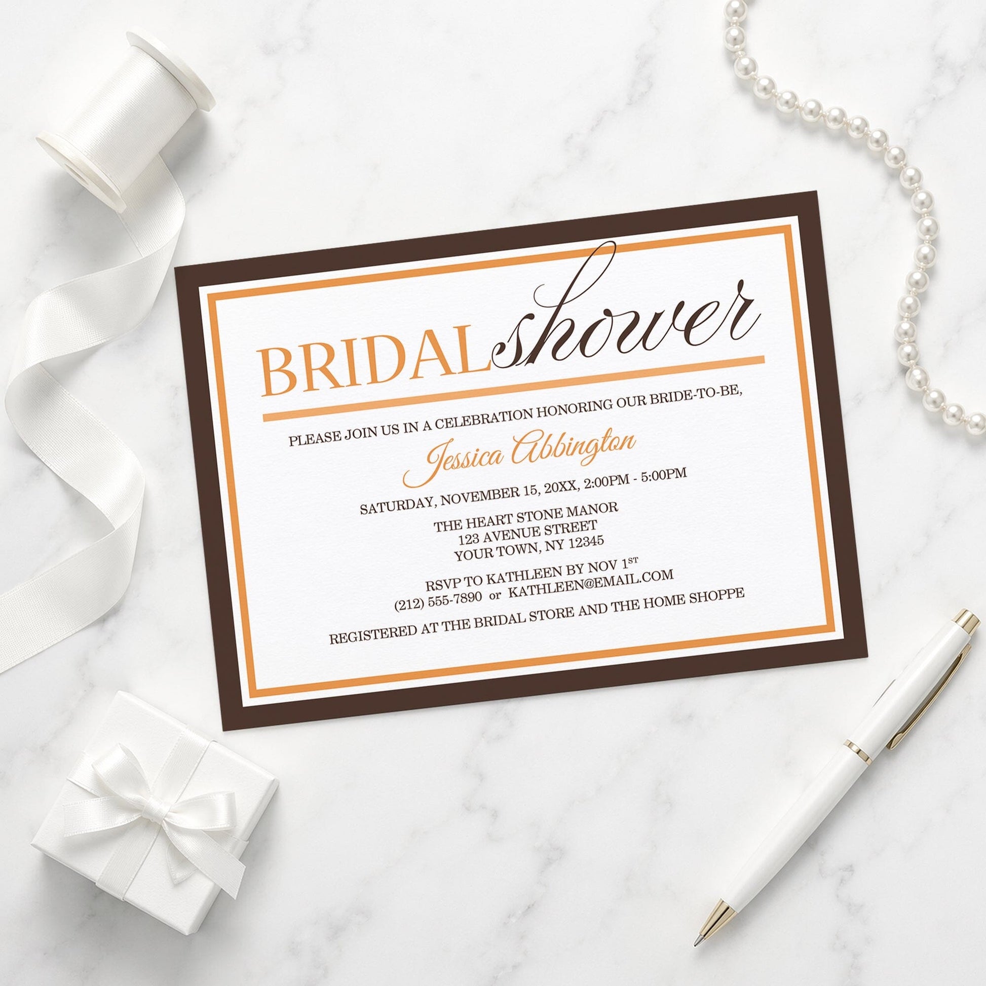 Modern Orange and Brown Autumn Bridal Shower Invitation shown on a marble surface with a white gift box, pen, ribbon, and pearls.