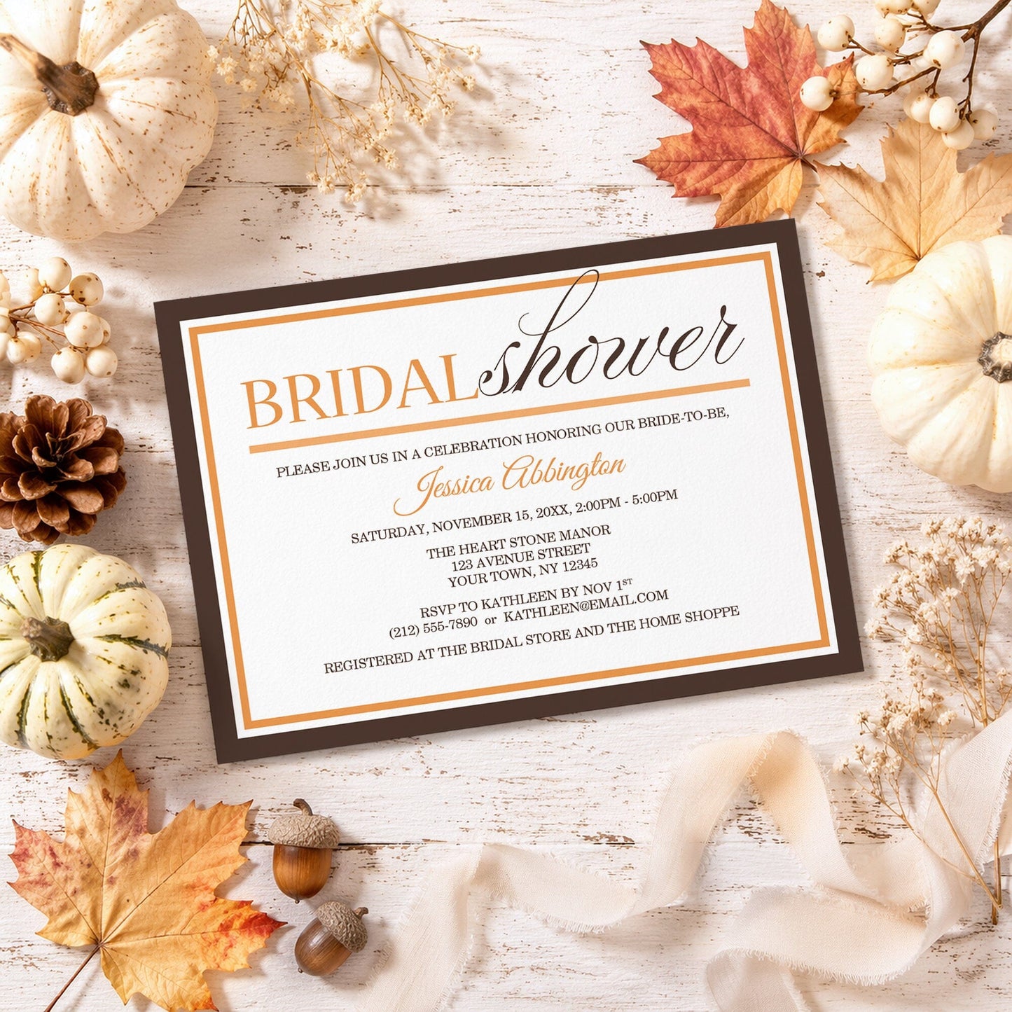 Modern Orange and Brown Autumn Bridal Shower Invitation shown on a rustic surface with fall leaves and autumn decor.