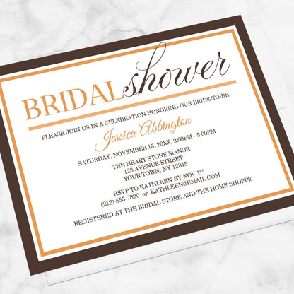 Modern Orange and Brown Autumn Bridal Shower Invitation shown at an angle on a marble surface with a white envelope.