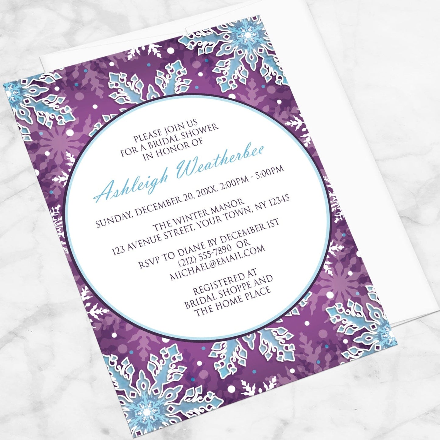 Modern Purple Blue Snowflake Bridal Shower Invitation shown at an angle on a marble surface with a white envelope.