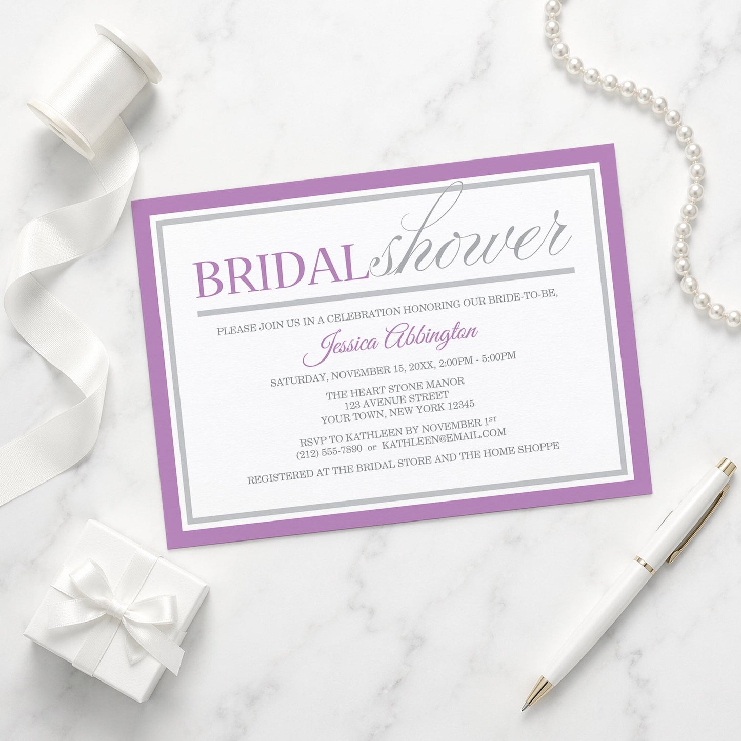 Modern Purple and Gray Bridal Shower Invitation shown on a marble surface with a white gift box, pen, ribbons, and pearls.