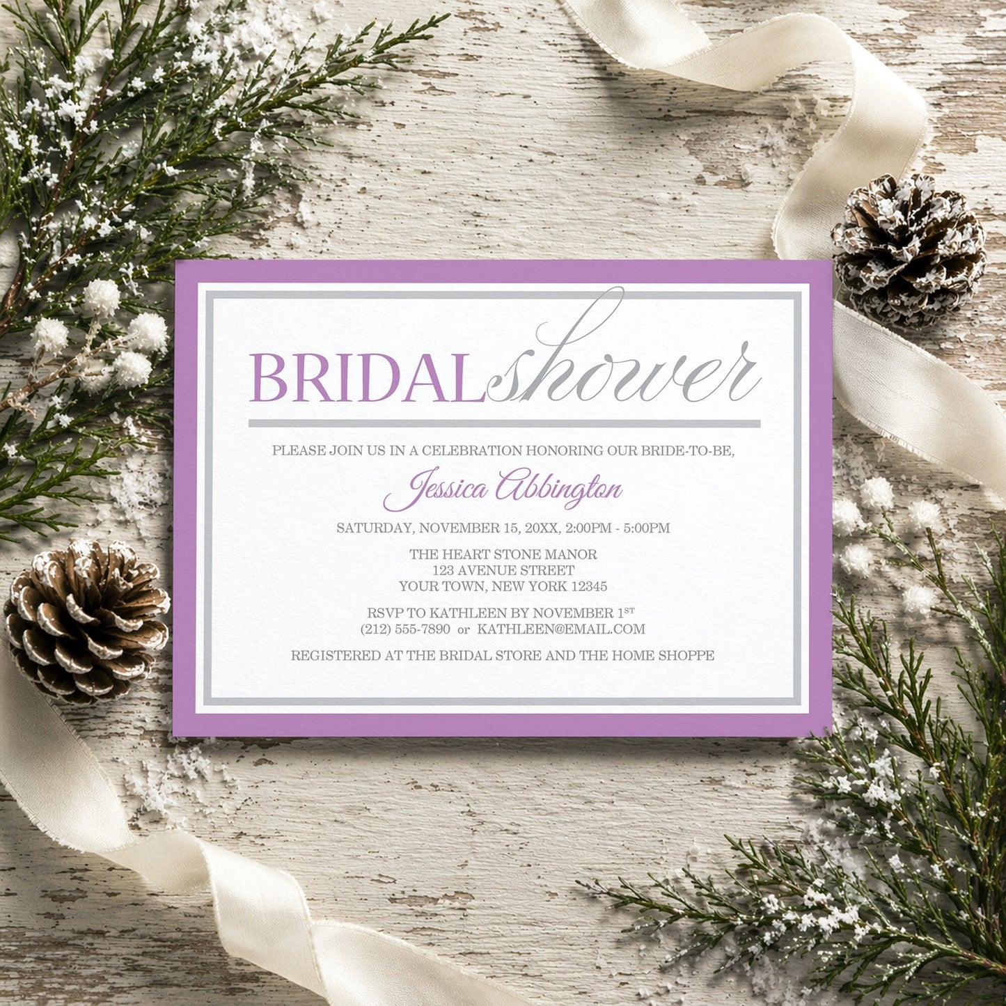 Modern Purple and Gray Bridal Shower Invitation shown on a rustic surface with winter greenery, pine cones, and ribbons.