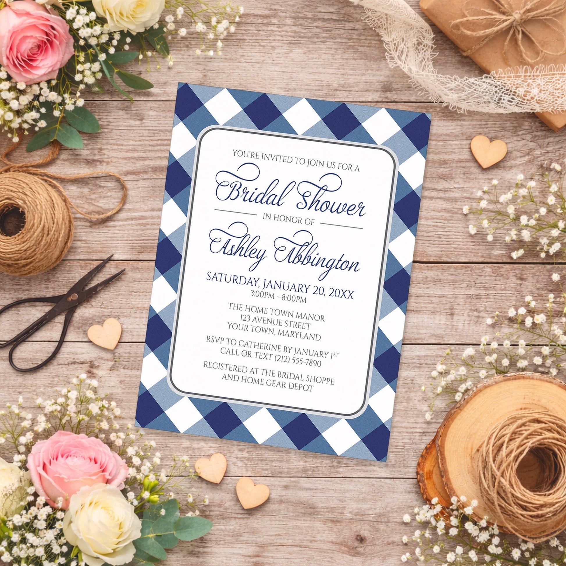 Navy Blue Gingham Bridal Shower Invitation with blue and white checkered border on a wooden surface with spring and summer flowers, small wood hearts, and twine.
