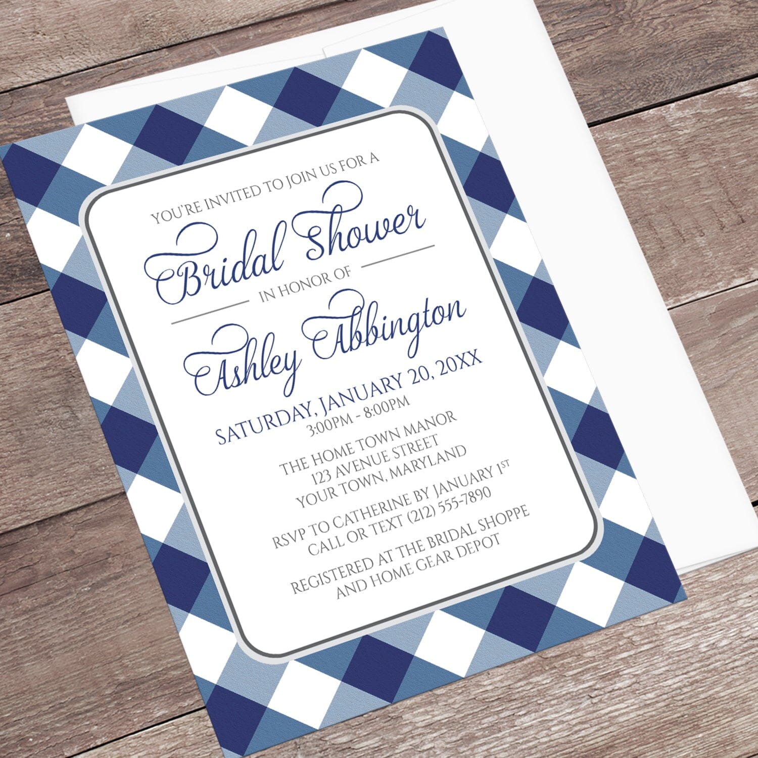Navy Blue Gingham Bridal Shower Invitation with blue and white checkered border shown at an angle on a wooden surface with a white envelope.