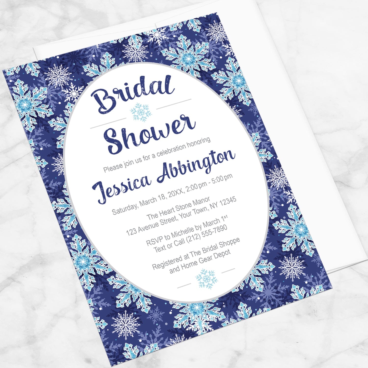 Navy Blue Snowflake Bridal Shower Invitation shown at an angle on a marble surface with a white envelope.