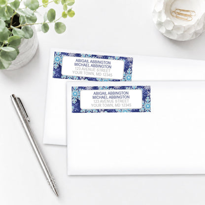 Navy Blue Snowflake Winter Address Labels on white envelopes with a pen and plant in the background.
