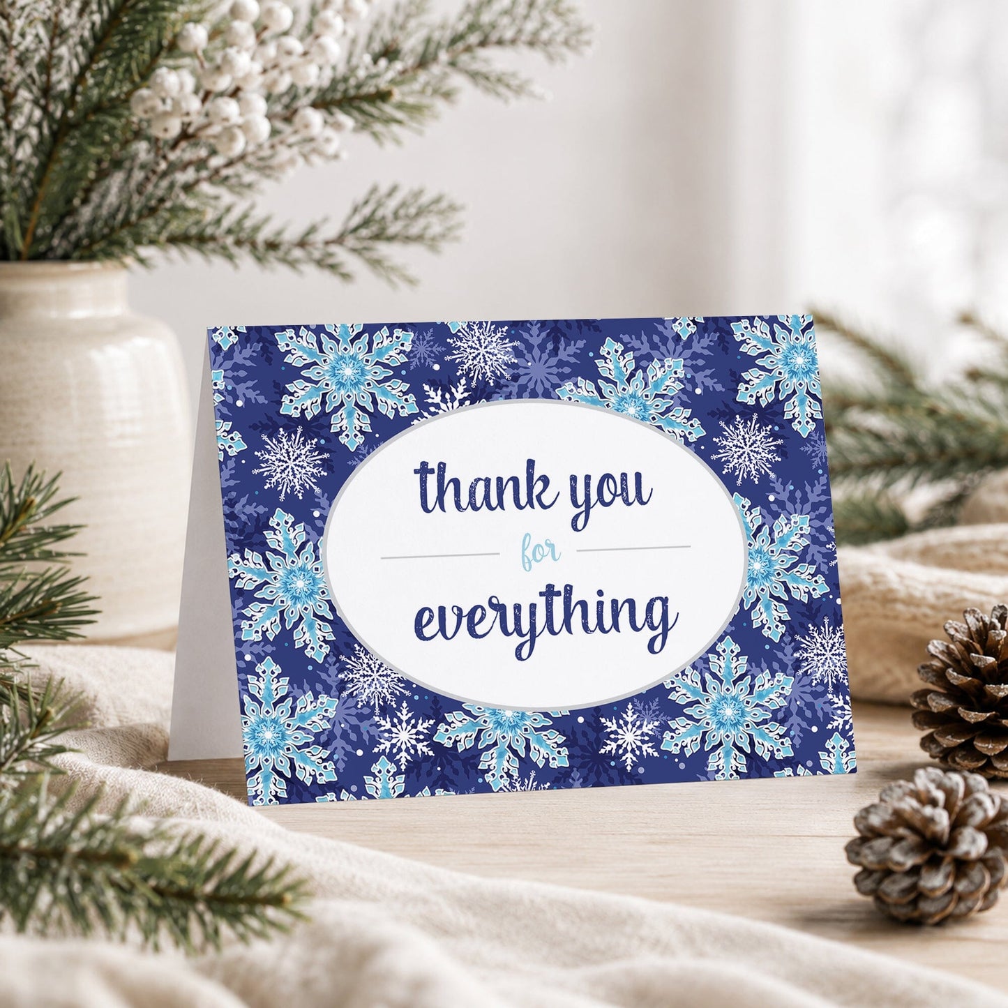 Navy Blue Snowflake Winter Thank You Card, with a "thank you for everything" message, shown on a tabletop with a vase, winter greenery, and pine cones.