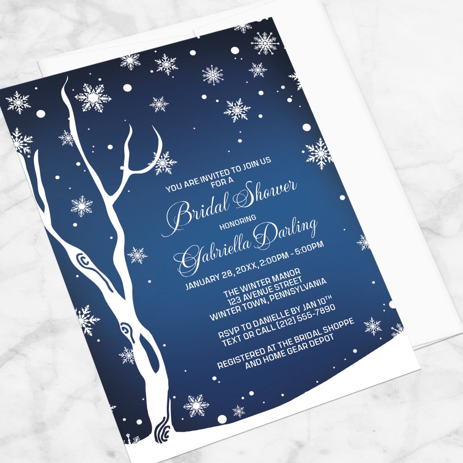 Navy Night Sky Snowflake Winter Bridal Shower Invitation shown at an angle on a marble surface with a white envelope.