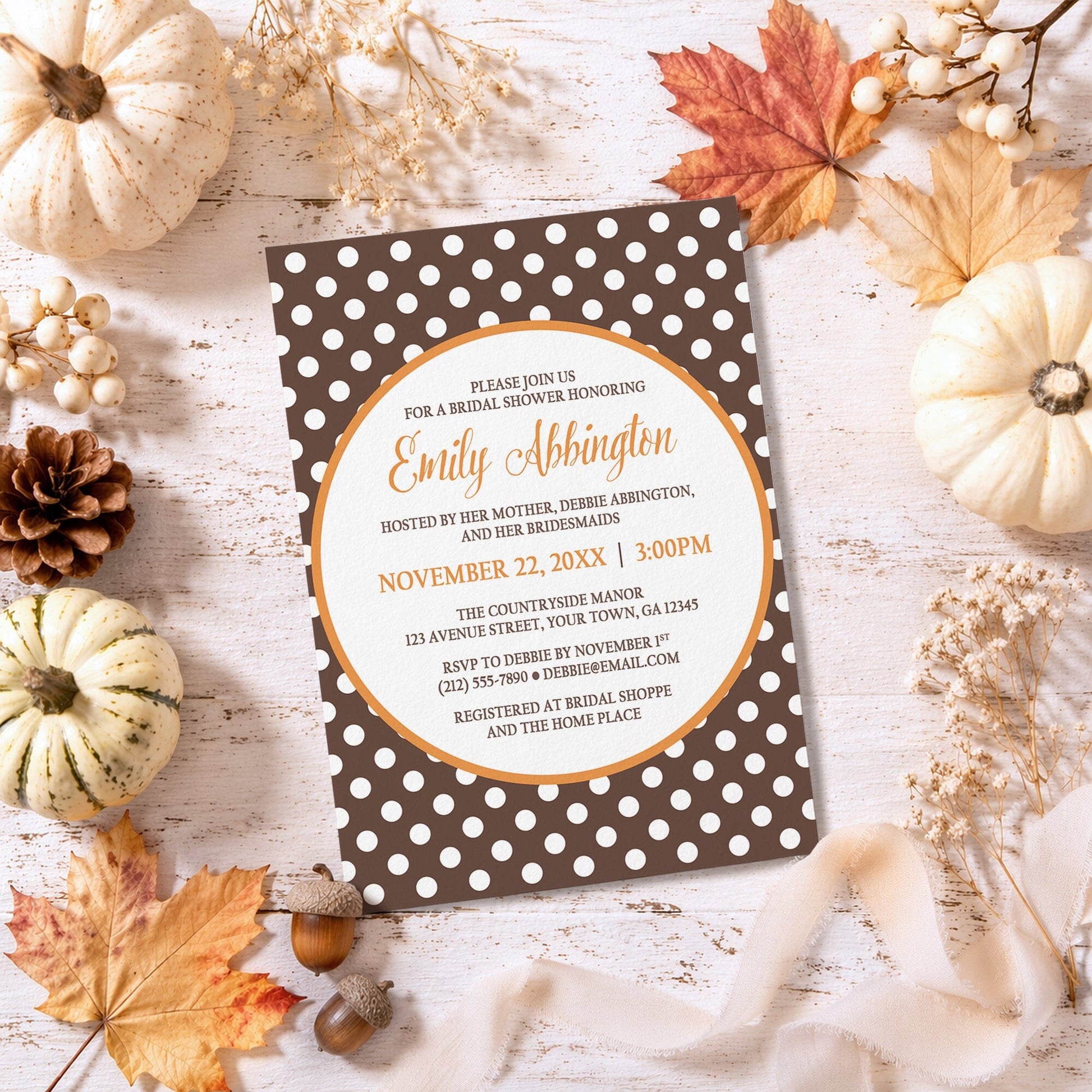 Orange Brown Polka Dot Bridal Shower Invitation on a rustic surface with autumn decorations.