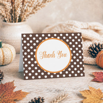 Orange Brown Polka Dot Thank You Card shown on a tabletop with a vase, fall leaves, and autumn decor.