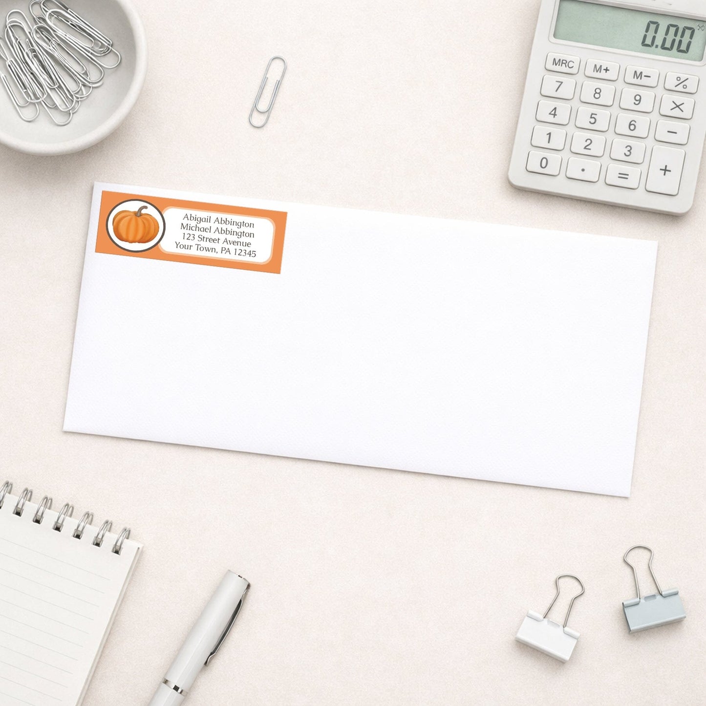 Orange Pumpkin Address Label shown on a white envelope with everyday office supplies