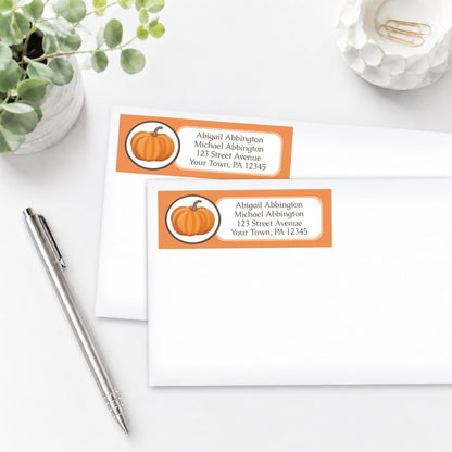 Orange Pumpkin Address Labels shown on white envelopes, on a white surface with a plant and a pen.