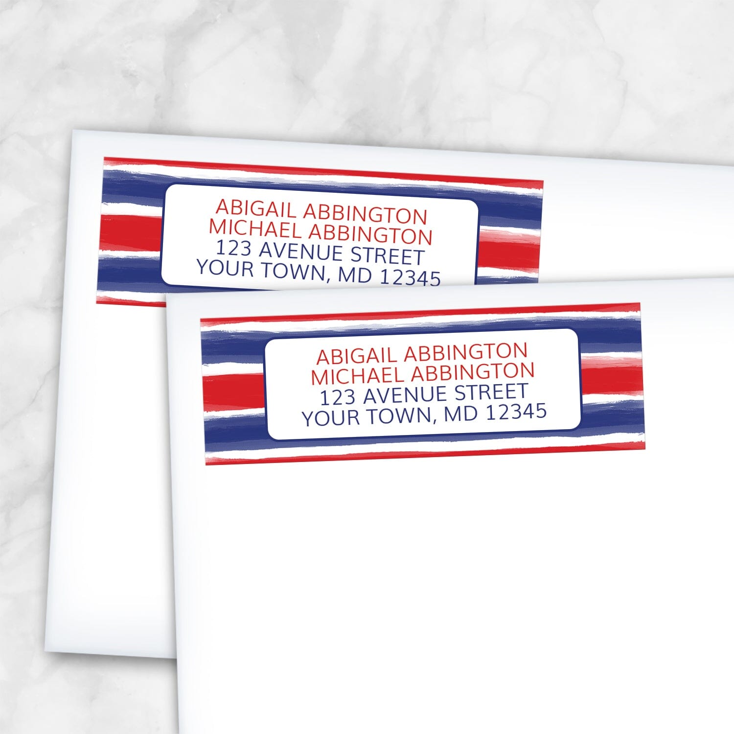 Patriotic Paint Brush Strokes Address Labels with blue and red artistic stripes across the labels and your address in red and blue on white in the center, shown on white envelopes on a marble surface.