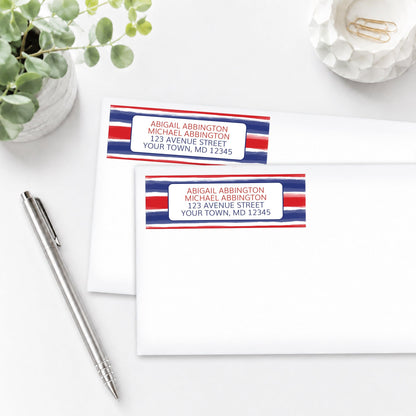 Patriotic Paint Brush Strokes Address Labels shown on white envelopes on a white surface with a plant and a pen.