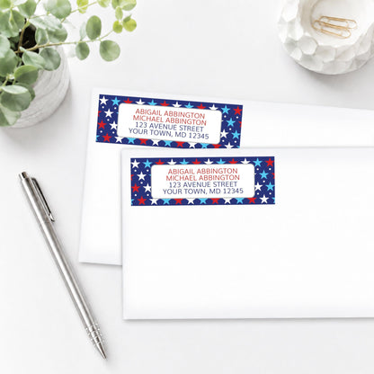 Patriotic Red White Blue Stars Address Labels on white envelopes shown on a white surface with a plant and a pen.