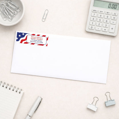 Envelope with address label featuring an American flag design on a desk with office supplies.