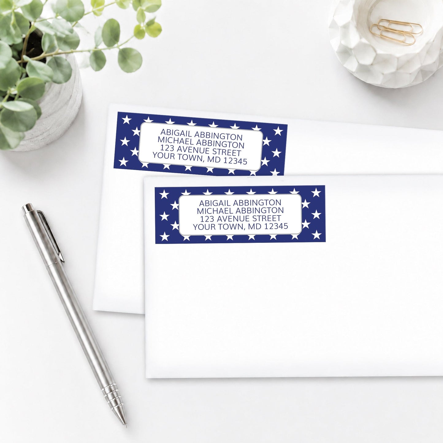 Patriotic White Stars on Blue Address Labels on white envelopes, on a white surface with a pen and plant.